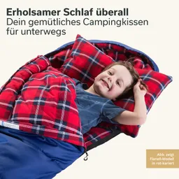 Ein Kind liegt in einem Schlafsack mit rot-karierter Decke und Kissen. Es lächelt und hat einen blauen T-Shirt an.