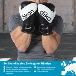 Person trägt schwarze Boxhandschuhe mit weißem Logo. Hintergrund ist eine Wand aus Beton. Text und Symbole unten auf dem Bild.