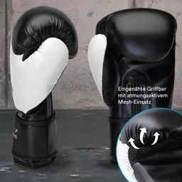 Zwei schwarze Boxhandschuhe mit weißen Einsätzen. Im Hintergrund eine graue Wand. Zusätzliche Informationen zu Materialien.
