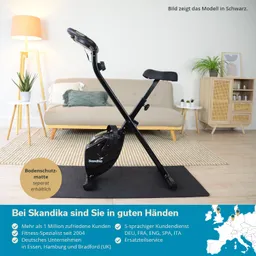 Schwarzes Fitnessgerät mit x-förmigem Gestell, Sitz und Pedalen auf einer Bodenschutzmatte in modernem Wohnzimmer.