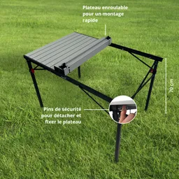 Ein faltbarer Tisch mit einem rollbaren Oberteil, unterstützt von einem schwarzen Metallgestell auf grünem Gras.