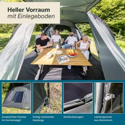 Vier Personen sitzen entspannt in einem Zelt auf Stühlen, um einen Tisch mit Snacks und Getränken. Im Hintergrund Bäume.