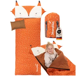 Ein orangefarbener Schlafsack mit Fuchs Kopfteil und Muster. Daneben ein Rucksack in ähnlicher Farbe. Eine Person sitzt im Schlafsack.