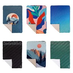 Sechs Decken mit verschiedenen Designs: Berge, Pflanzenmuster, Farbverlauf und Schwarz mit Logo. Jede Decke hat eine andere Oberseite und eine helle Unterseite.