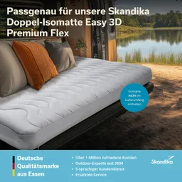 Doppelbett mit grauer Matratze und orangefarbenem sowie grauem Kissen, in einem Van, mit Blick auf einen See im Hintergrund.
