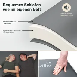 Das Bild zeigt eine Matratze mit einer grauen Softtouch-Oberfläche und einer ergonomischen Schaumstoffschicht. In der unteren Hälfte sind zwei Personen zu sehen, die nebeneinander liegen und sich anlächeln. Eine Hand berührt die Matratze.