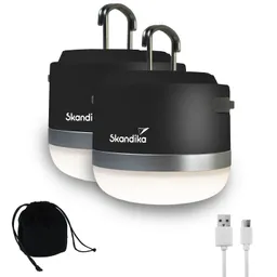 Zwei schwarze Campinglampen mit Silberelement, Aufhängemöglichkeiten und USB-Ladekabel neben einem schwarzen Beutel.