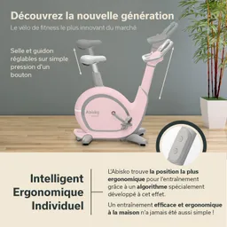Fitness-Bike in Rosa mit einstellbarem Sattel und Lenker. Hintergrund in neutralem Farbton und Pflanze im Raum.