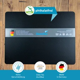 Schwarze Matte mit strukturiertem Design und grauem Aufkleber, Informationen über Material und Herkunft. Untergrund aus Holz.