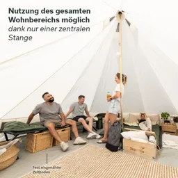 Innere eines großen Zeltes mit zentraler Stange. Vier Personen sitzen oder stehen, ein Handtuch und eine Pflanze sind sichtbar. Kenntnisse der Einrichtung.
