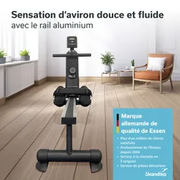 Rudergerät mit Aluminium-Schiene in einem modernen Raum. Holzfußboden, Pflanze und Sessel im Hintergrund.
