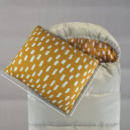 Kissen mit gelb-weißer Musterung liegt auf einer geöffneten Schlafsacköffnung in beige. Maße sind angegeben.