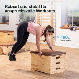 Beige Holzkiste mit brauner Polsterung. Eine Person führt eine Gymnastikübung auf der Kiste aus. Helle Umgebung.