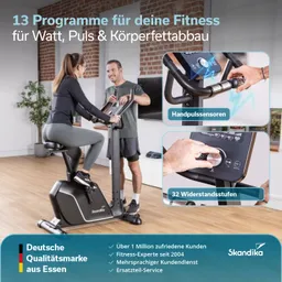 Fitnessgerät in einem Raum mit Holzfußboden. Eine Person sitzt darauf, eine weitere steht daneben. Display mit Funktionen sichtbar.