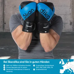Ein Mann mit schwarzen und blauen Boxhandschuhen hält diese vor seinem Gesicht. Er trägt ein graues T-Shirt. Im Hintergrund ist eine schlichte Wand zu sehen. Unten im Bild befinden sich Text und Symbole zur Unternehmensbeschreibung.