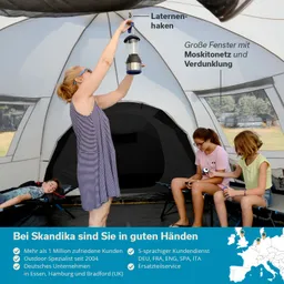 Eine Person hängt eine Laterne in einem Zelt auf. Im Hintergrund sitzen zwei Personen auf Campingsesseln. Das Zelt hat große Fenster mit Moskitonetz.