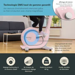 Eine Trainingsgerät, ein Heimtrainer in Rosa, steht in einem hellen Raum. Im Vordergrund ist ein Fuß einer Person sichtbar, die gerade strampelt. Auf dem Gerät gibt es ein LED-Display, das Informationen anzeigt.