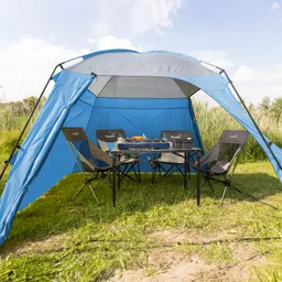 Blaues Zelt mit zwei Klappstühlen und einem Tisch. Auf dem Tisch stehen ein Grill und einige Utensilien. Grüne Wiese im Hintergrund.