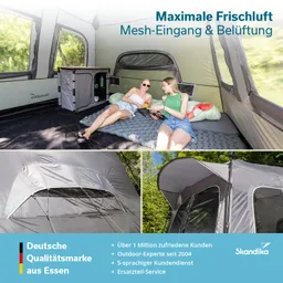 Zwei Personen sitzen in einem Zelt auf einer Matratze, umgeben von grauen Zelten und einem Tisch. Eine Person liest.