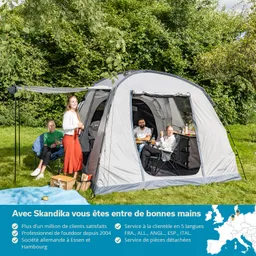 Zelt in der Natur mit vier Personen, die entspannt sitzen. Eine Person steht mit Flasche, drei sitzen an einem Tisch mit Essen.