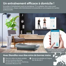 Wohnzimmer mit einem Trainingsgerät in der Mitte, einem Fernseher, einer Pflanze und einem Holzregal. Smartphone zeigt Trainingsprogramm.