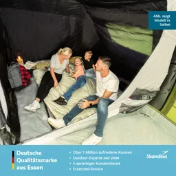 Familie im Zelt, sitting auf Schlafmatratzen, umgeben von Rucksäcken und einer Taschenlampe.