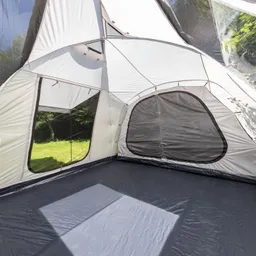 Innenansicht eines Zelt mit grauen und weißen Wänden, zwei Fenster und einem dunklen Bodenbelag. Außenblick auf Grasfläche.