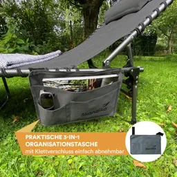 Graue Organisations-Tasche hängt an einem Liegestuhl. Ein Handy und ein Buch sind sichtbar. Im Hintergrund Gras und Bäume.