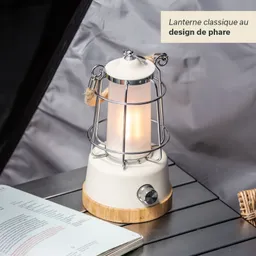 Eine klassische Laterne im Design eines Leuchtturms steht auf einem Tisch. Die Laterne hat einen weißen, zylindrischen Körper mit einem Metallgitter und einem Holzsockel. Daneben liegt ein aufgeschlagenes Buch.