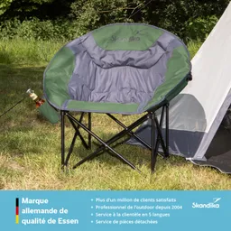 Grauer Campingstuhl mit grünen Akzenten steht auf Rasen, neben einem Zelt. Eine Flasche in Halterung am Stuhl.