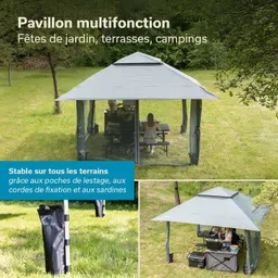 Grau-grüner Pavillon auf einer Wiese, mit mehreren Personen an einem Tisch. Im Hintergrund Bäume und eine grüne Umgebung.