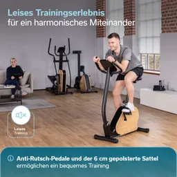 Ein Mann sitzt auf einem Fitnessgerät und trainiert. Im Hintergrund sitzt eine Person auf einem Sofa und nutzt ein Tablet.