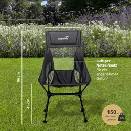 Schwarzer Campingstuhl mit Netzeneinsatz auf grünem Gras, umgeben von lila Blumen. Maße: 96 cm hoch, 57 cm breit, 45 cm Sitzhöhe.