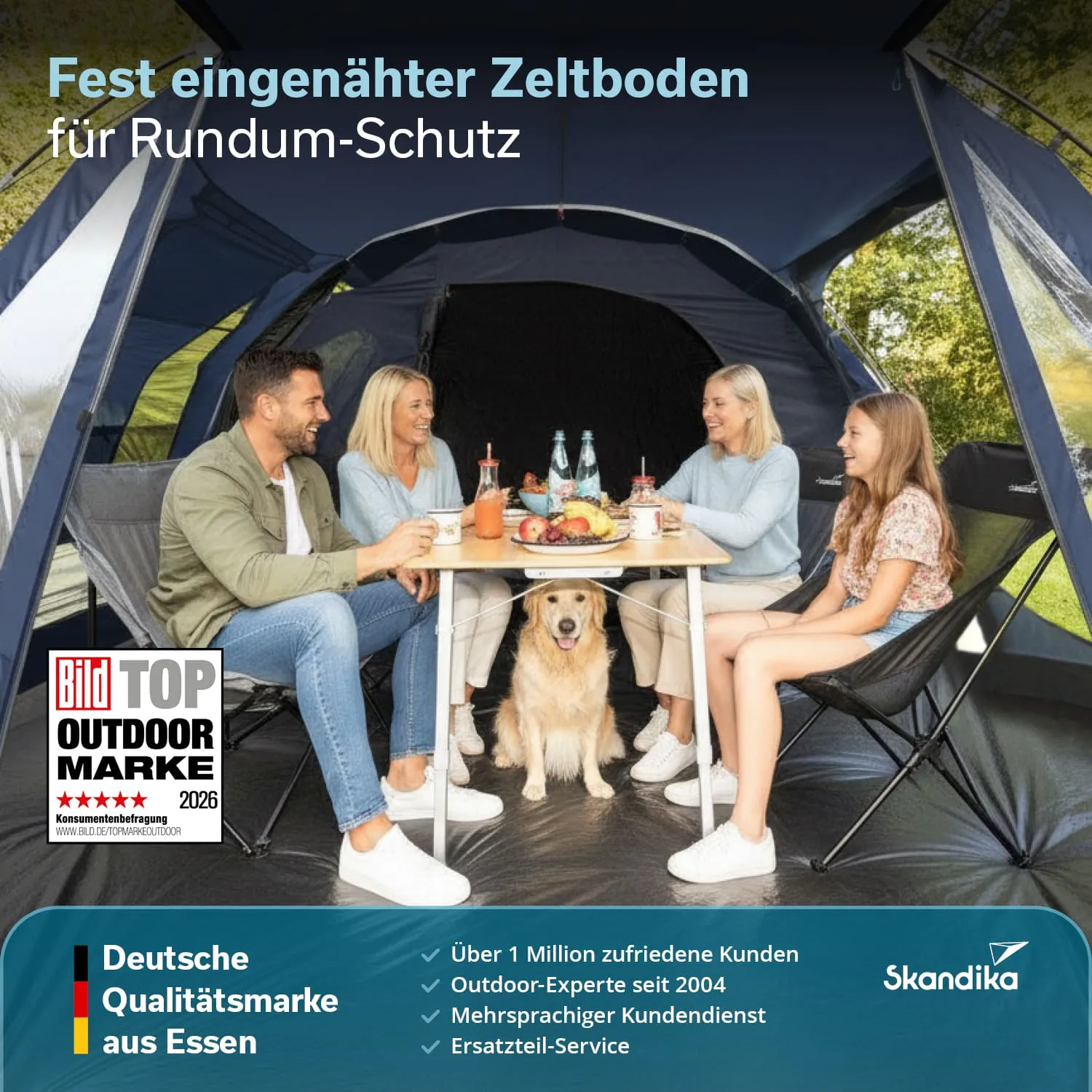 Vier Personen sitzen um einen Tisch in einem Zelt, gemeinsam mit einem Hund. Getränke und Snacks stehen auf dem Tisch.
