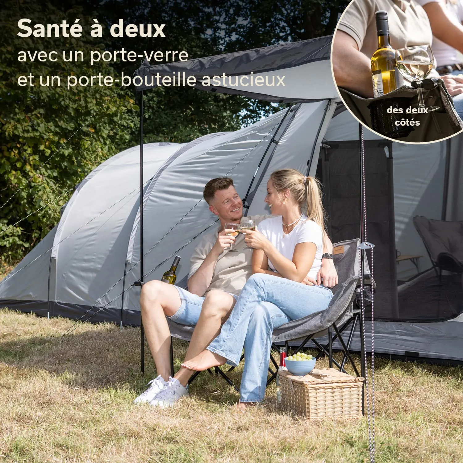 Paar sitzt entspannt in Campingstühlen unter einem Zelt. Beide halten Gläser und lächeln sich an. Neben ihnen stehen eine Weinflasche und ein Korb mit Snacks.