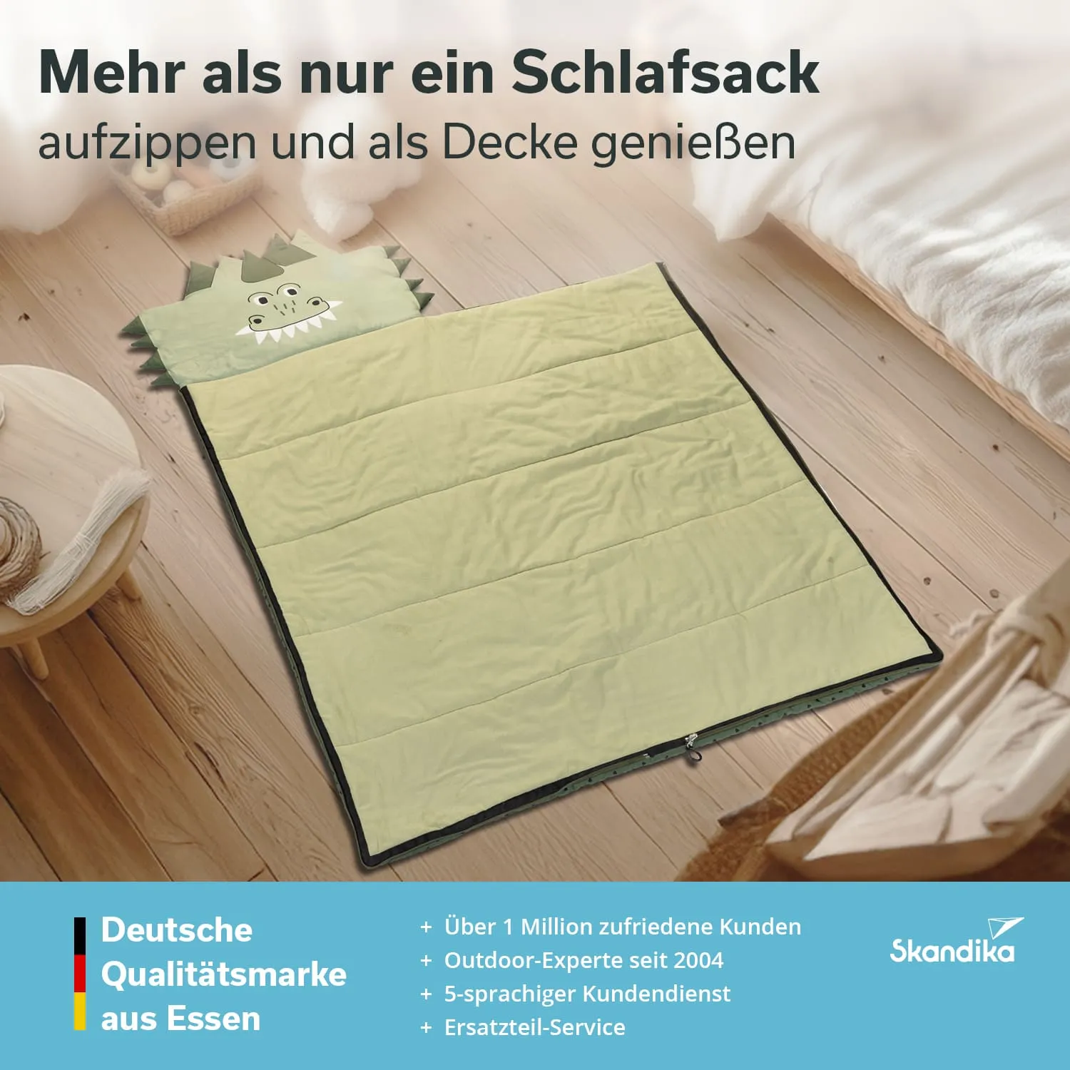 Grüner Schlafsack mit Tiermotiv, auf dem Boden liegend, umgeben von Holzboden und einer Decke im oberen Bereich.
