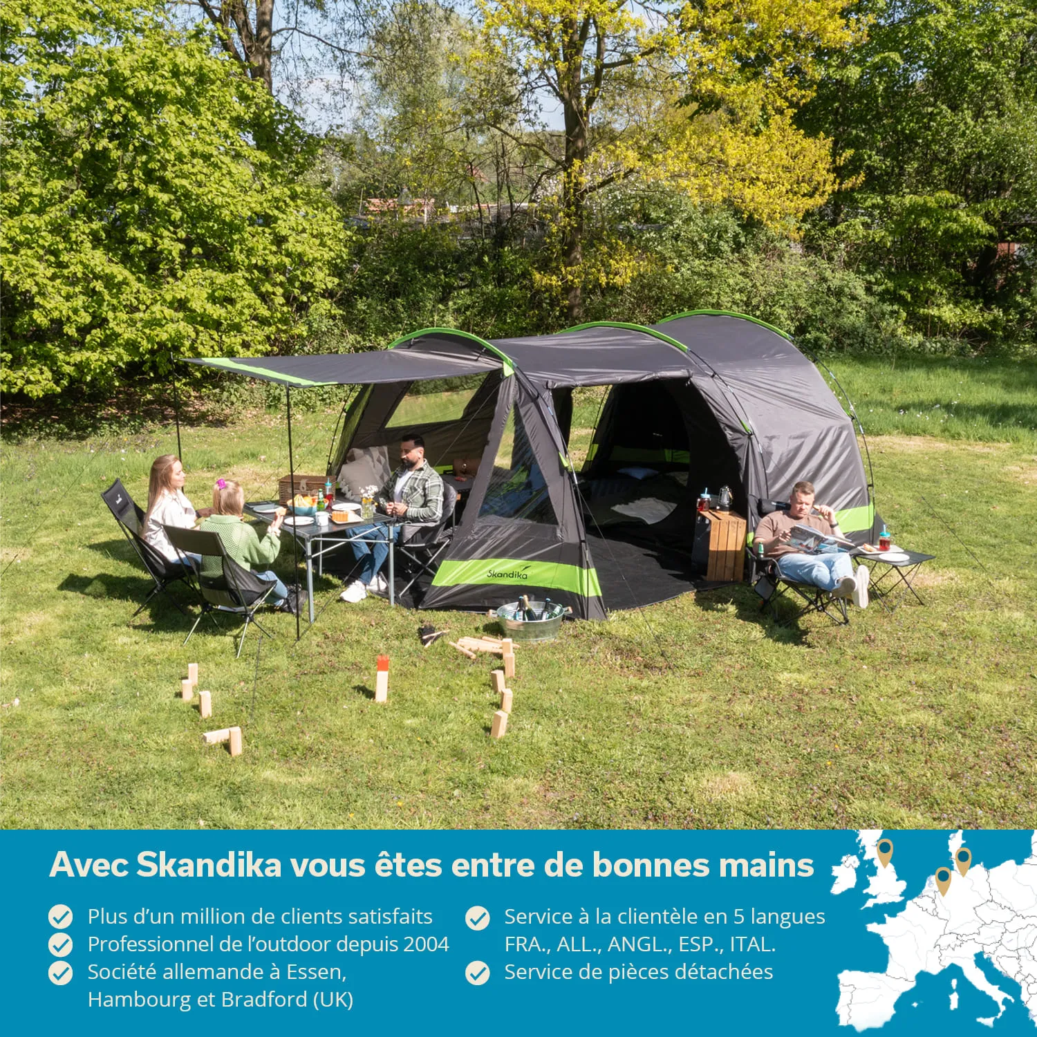 Campingzelt in einer grünen Wiese, drei Personen sitzen an einem Tisch mit Getränken und Essen, Spielzeug wird im Gras verteilt.