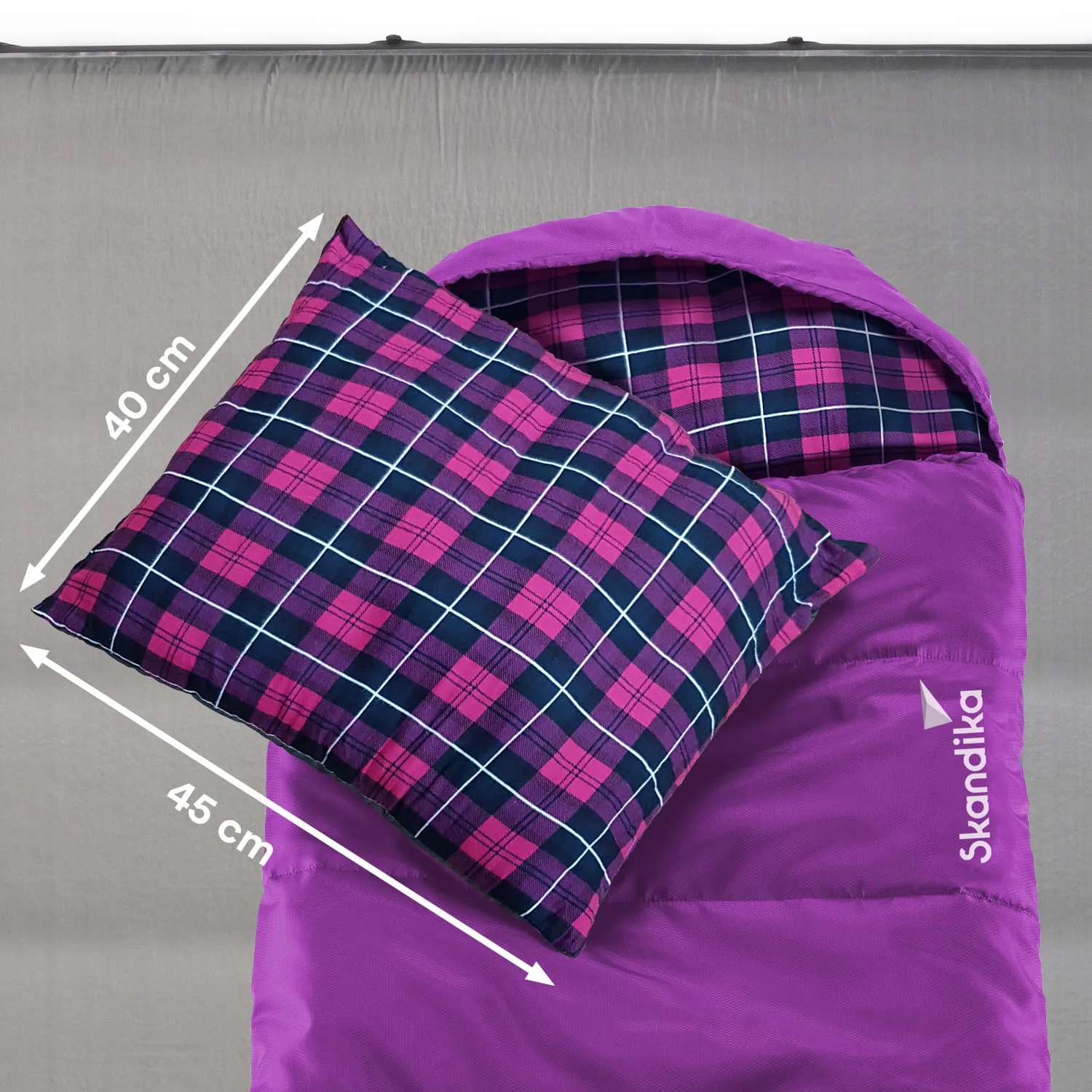 Schlafsack in lila mit aufgenähtem Logo und kariertem Kissen in Pink und Blau. Maße: Kissen 40 cm x 45 cm.