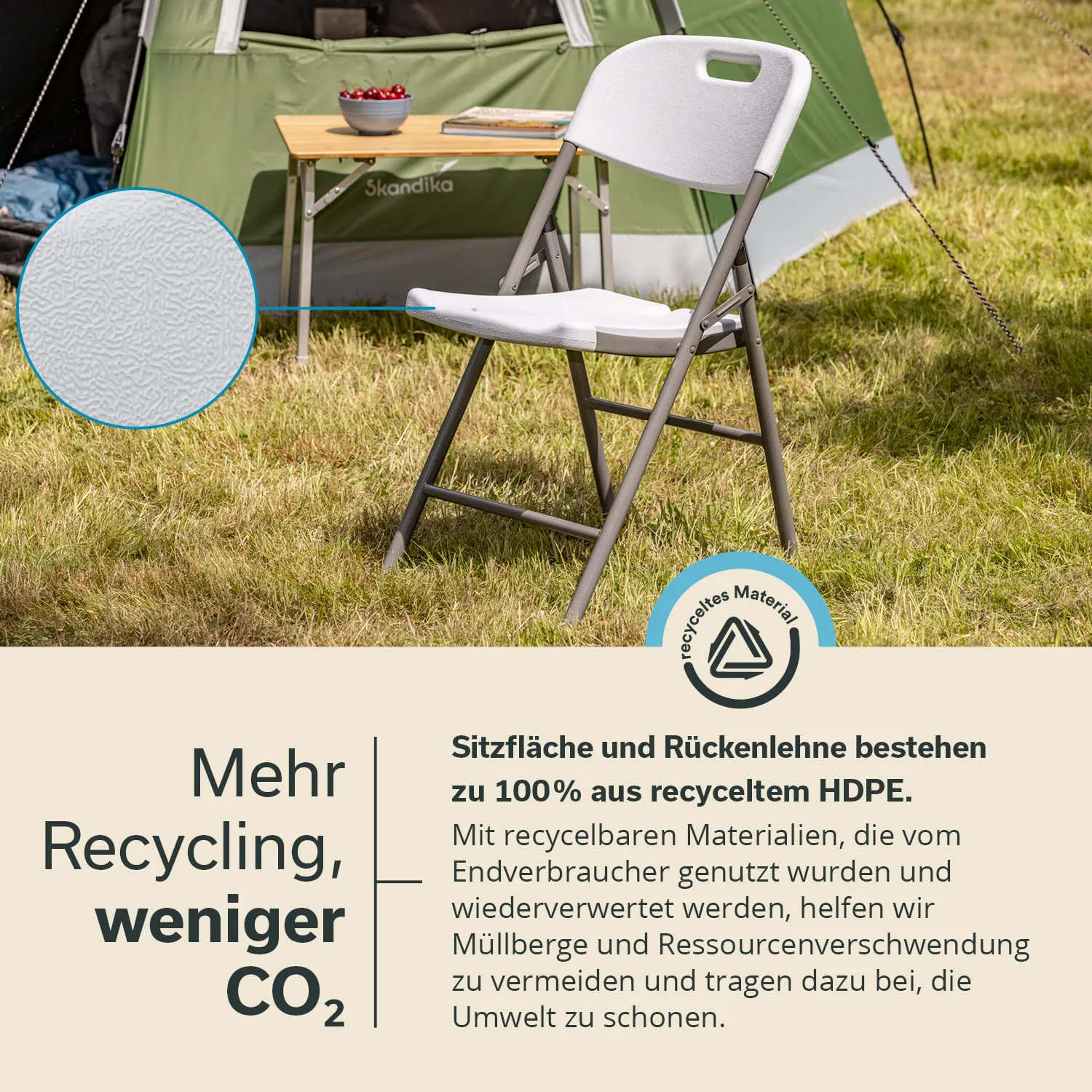 Faltstuhl mit grauem Metallgestell und weißem Sitz, neben einem Campingzelt auf einer Wiese. Ein Tisch mit Schüssel und Buch im Hintergrund.