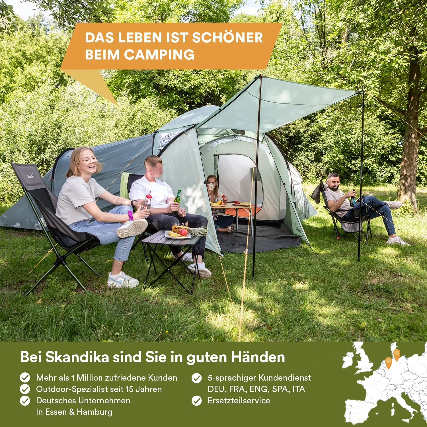 Drei Personen sitzen in Campingstühlen neben Zelten in einer grünen Umgebung. Es gibt einen Tisch mit Snacks und Getränken.
