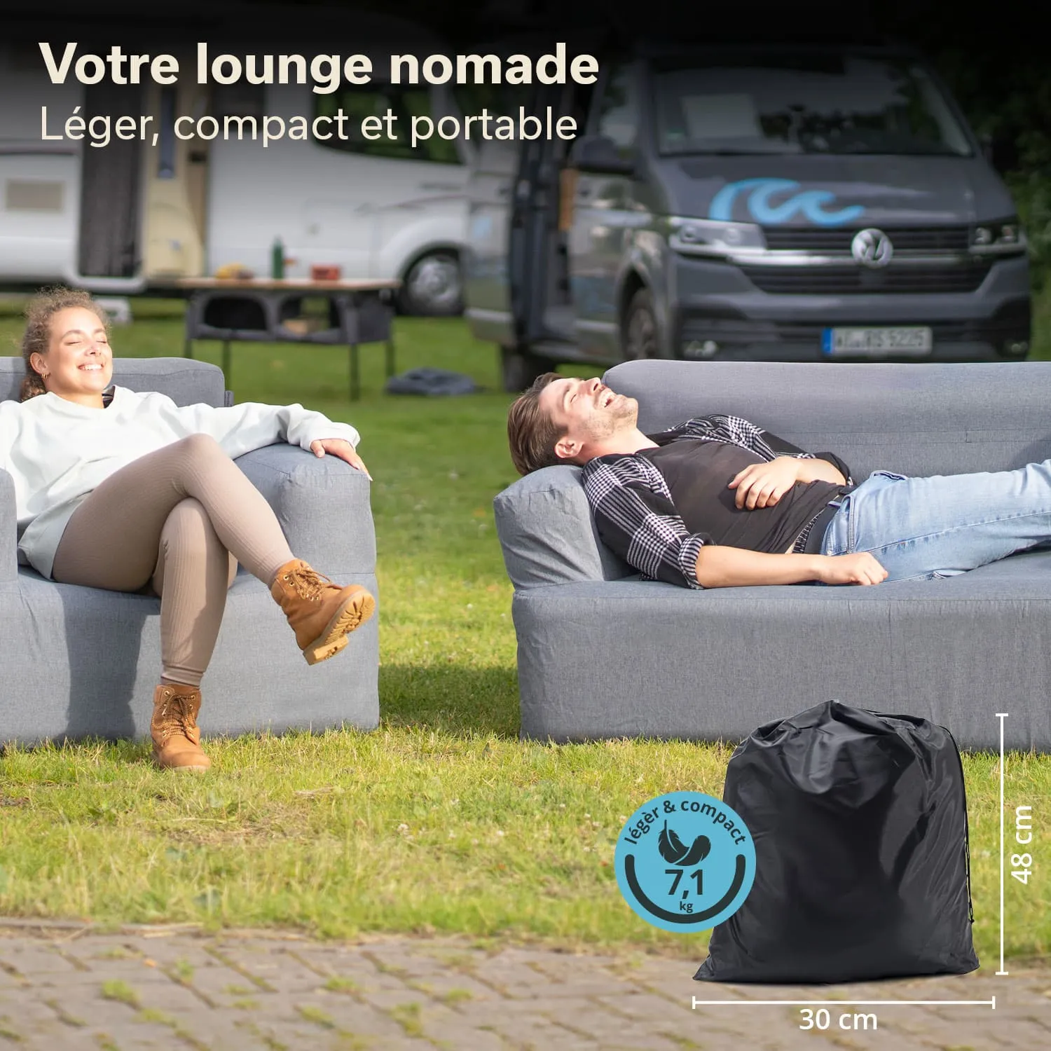 Zwei Personen sitzen entspannt auf grauen Sofas in einem grünen Außenbereich. Ein schwarzer Sack steht auf dem Boden.