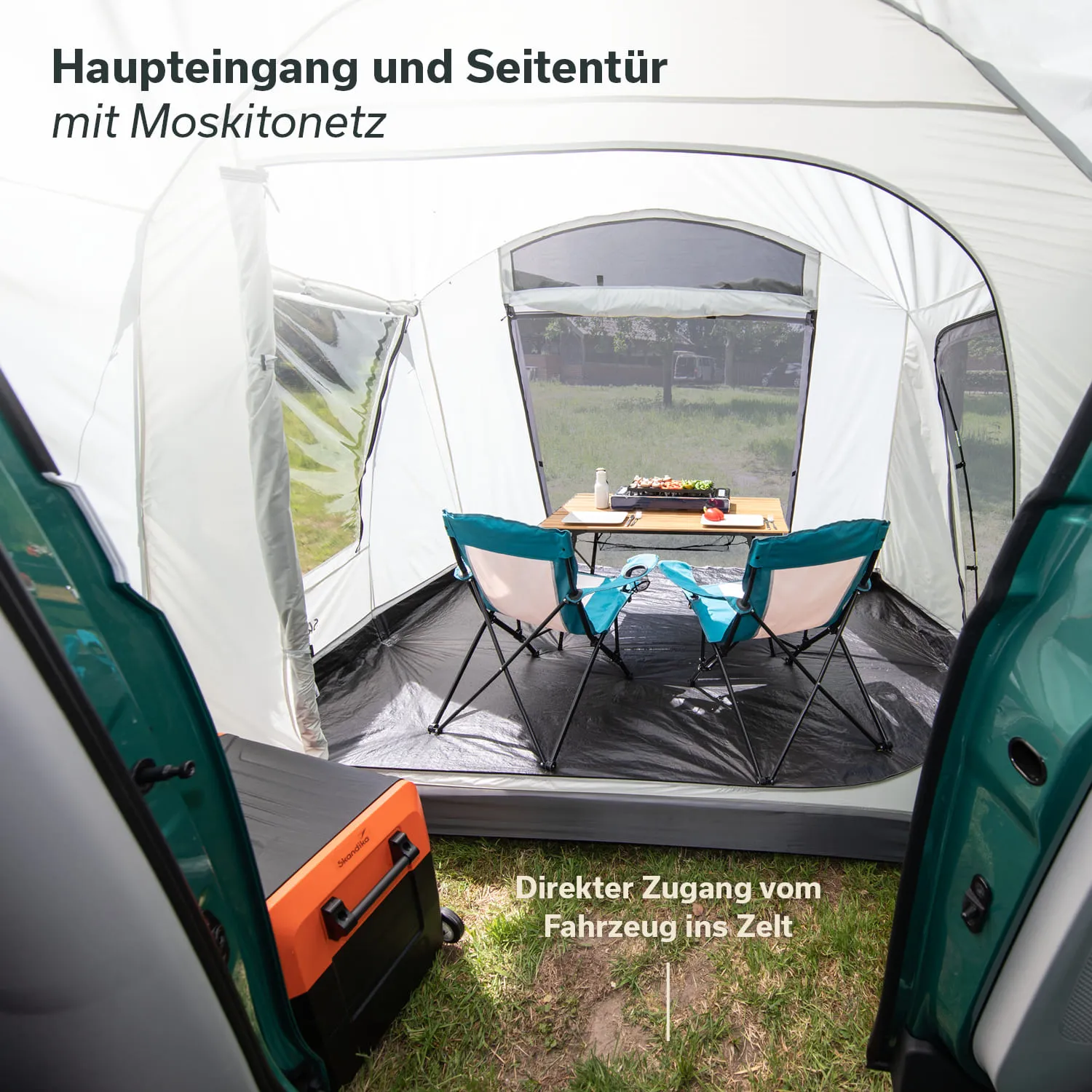 Zelt mit Moskitonetz, Innenansicht. Zwei Stühle und ein Tisch stehen darauf. Ein orangefarbener Kühlbox ist sichtbar.