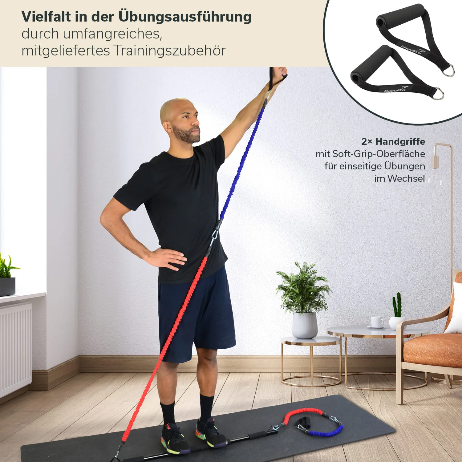 Eine Person steht auf einer Trainingsmatte und hält ein buntes Fitnessband mit zwei Handgriffen in der Hand. Im Hintergrund sind ein Pflanzengefäß und ein Stuhl sichtbar.