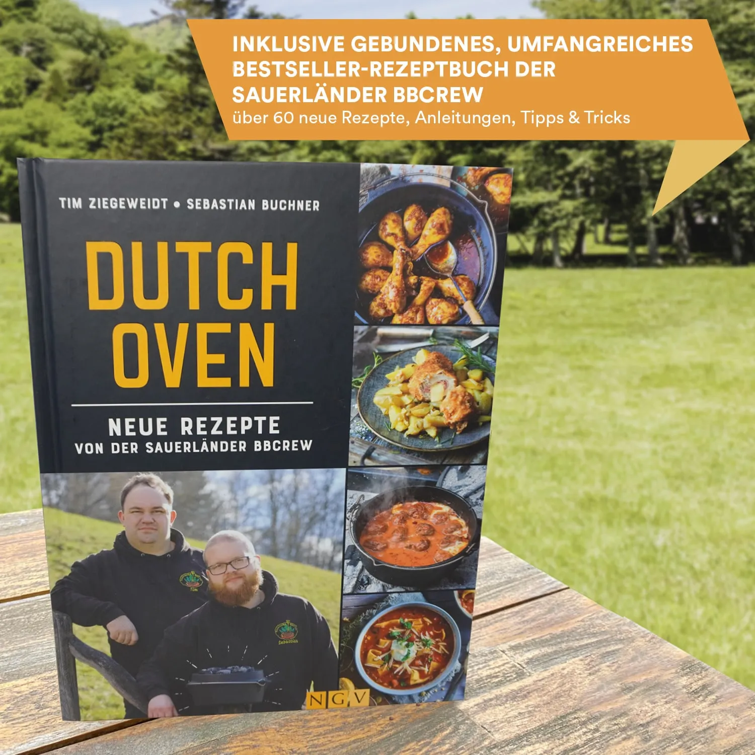 Ein Rezeptbuch mit dem Titel "Dutch Oven" liegt auf einem Holztisch. Auf dem Buchcover sind zwei Personen und verschiedene Gerichte abgebildet. Im Hintergrund ist eine grüne Wiese zu sehen.