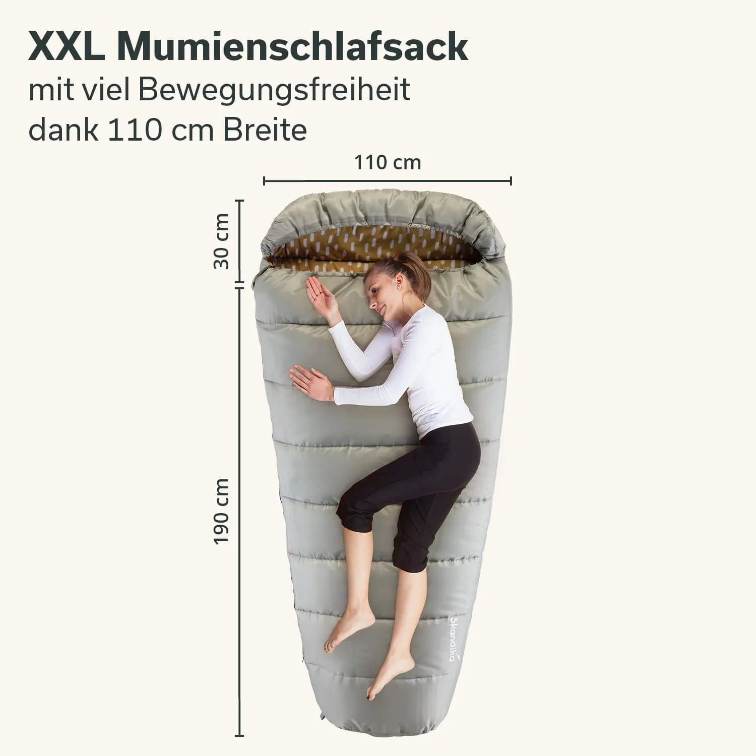 XXL Mumien-Schlafsack in grauer Farbe, Innenfutter mit Muster, Maßstab zeigt Breite 110 cm und Länge 190 cm, Person liegt darin.