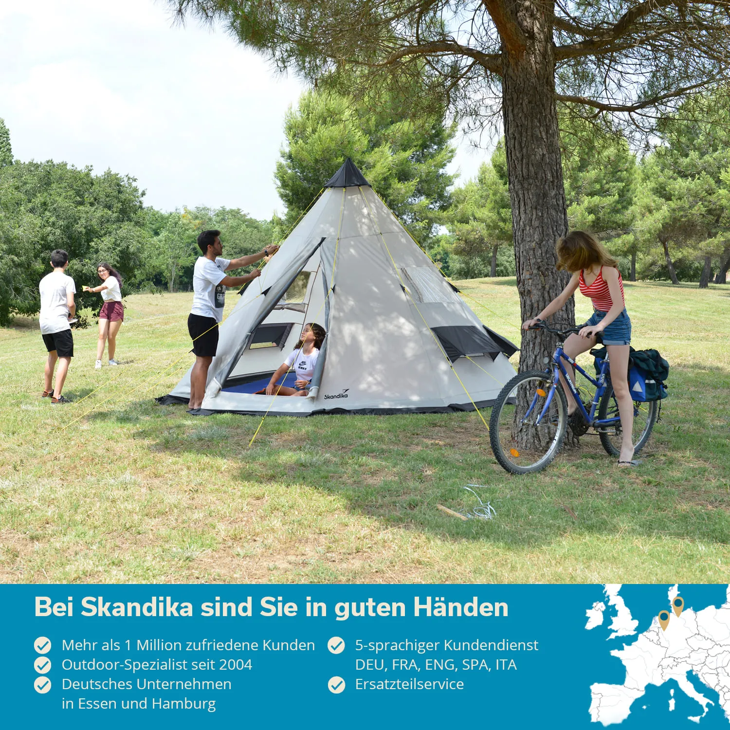 Trekkingzelt auf einer Wiese umgeben von Bäumen, mit Personen, die sich mit dem Zelt beschäftigen und einer Person auf einem Fahrrad.