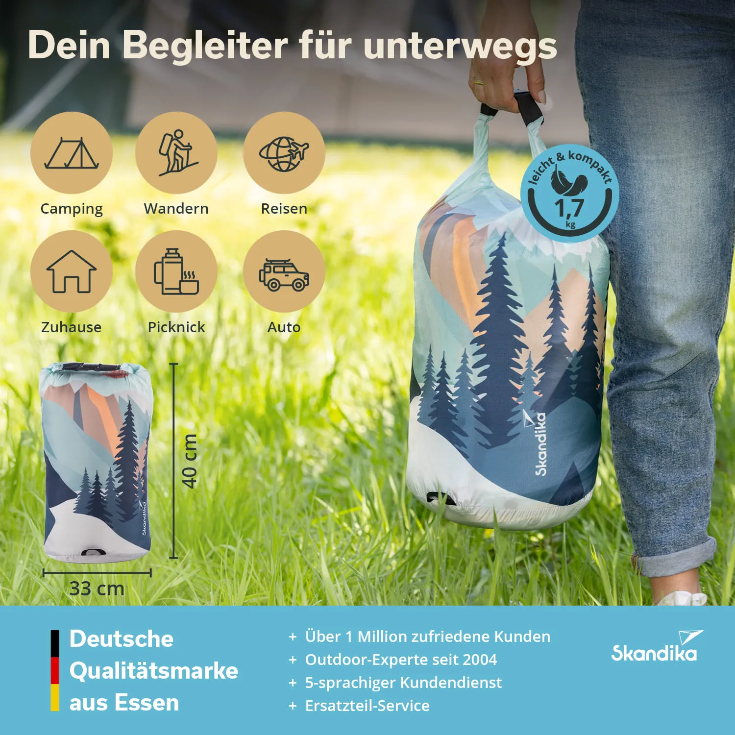 Kompakte Tasche mit buntem Landschaftsmuster, getragen von einer Person in Jeans, auf einer Wiese.