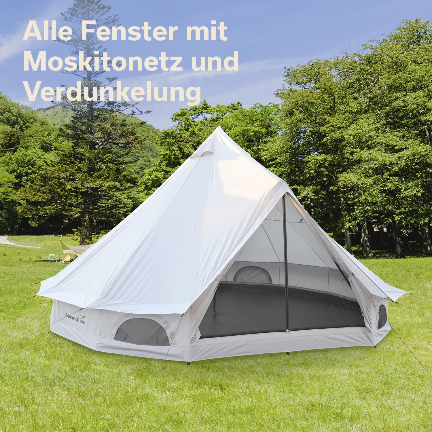 Weißes Zelt mit Moskitonetz und Verdunkelung, auf einer Wiese umgeben von Bäumen und einem blauen Himmel.