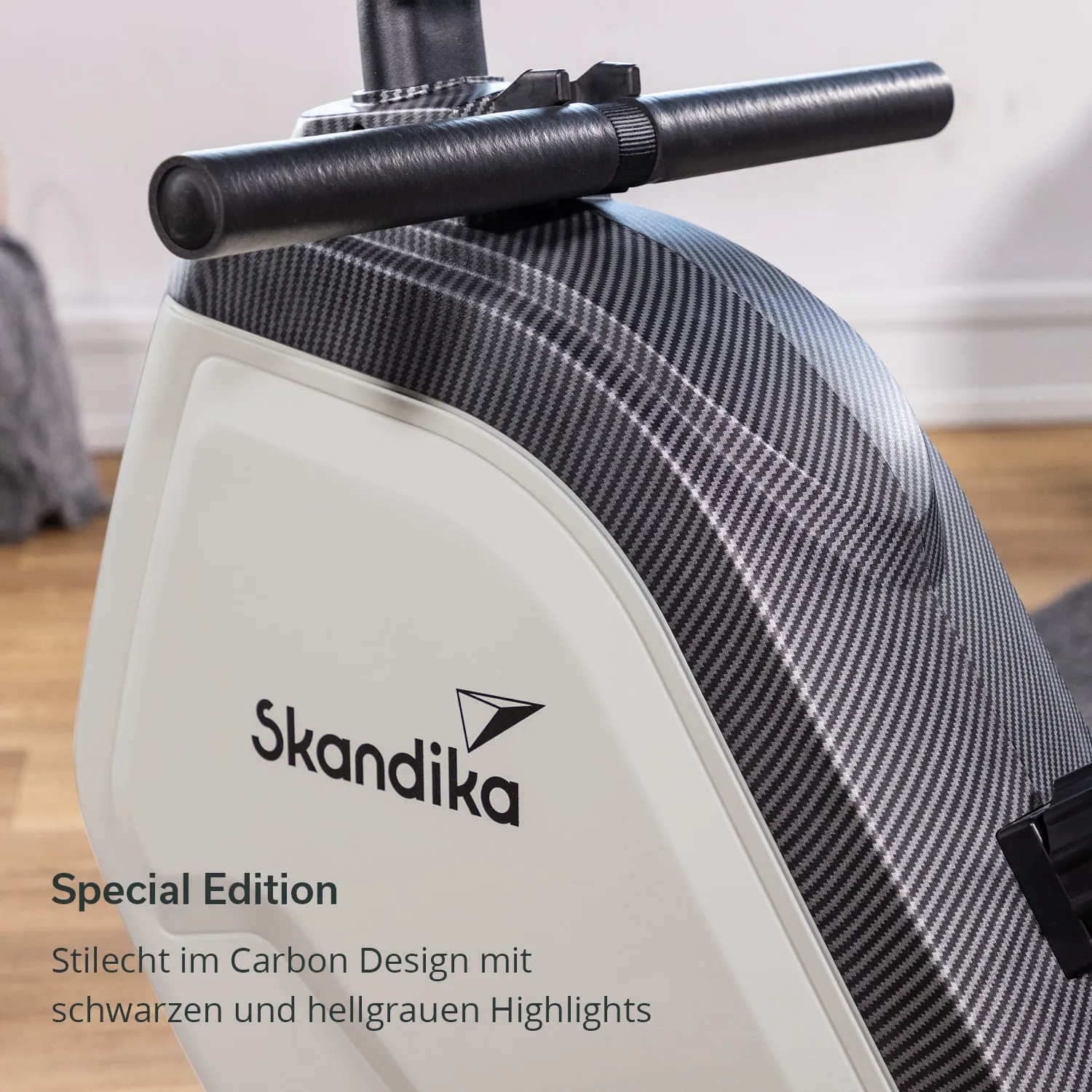 Fitnessgerät in Carbon-Design mit schwarzen und hellgrauen Akzenten. Logo „Skandika“ sichtbar. Umgebung hell und modern.
