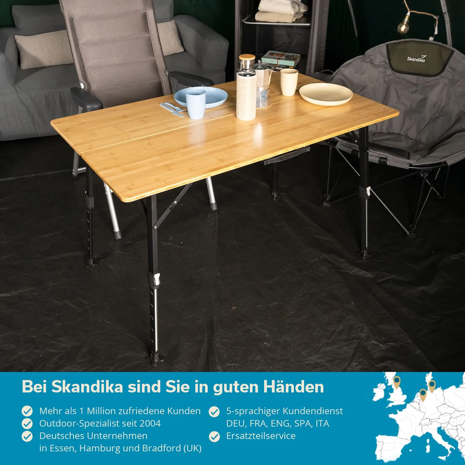 Holztisch mit zwei Tellern, Besteck und einer Thermoskanne. Im Hintergrund ein graues Sofa und ein Campingstuhl. Schwarzer Boden.